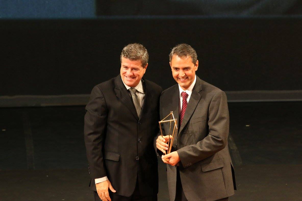 Claudio Guimarães Junior entrega troféu ao inventor Luiz Carmine.